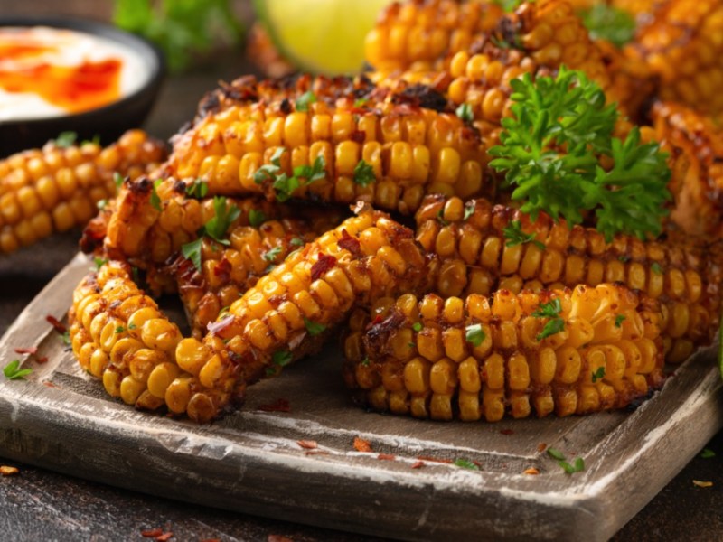 Una pila de costillas de maíz con perejil en un plato. Junto a él hay un cuenco con salsa.