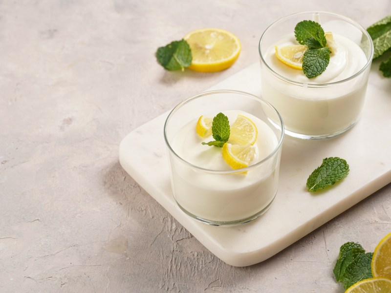 dos vasos de Syllabub, crema de limón inglesa, decorados con gajos de limón y menta, en una bandeja