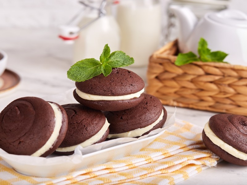 Varias whoopie pies en un plato, rodeadas por piezas de vajilla.