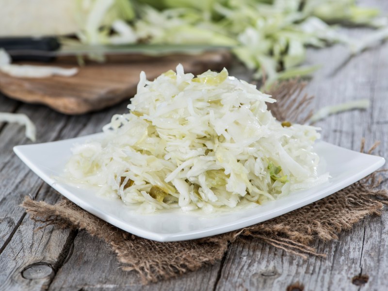 Ensalada de col en un plato cuadrado sobre una servilleta de tela gris.
