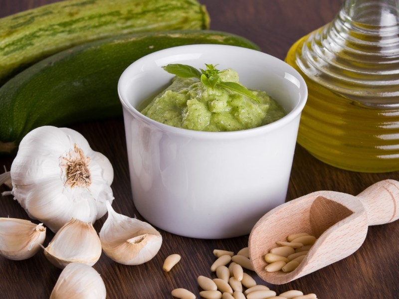 Un plato con pesto de calabacín. Alrededor, ingredientes frescos.
