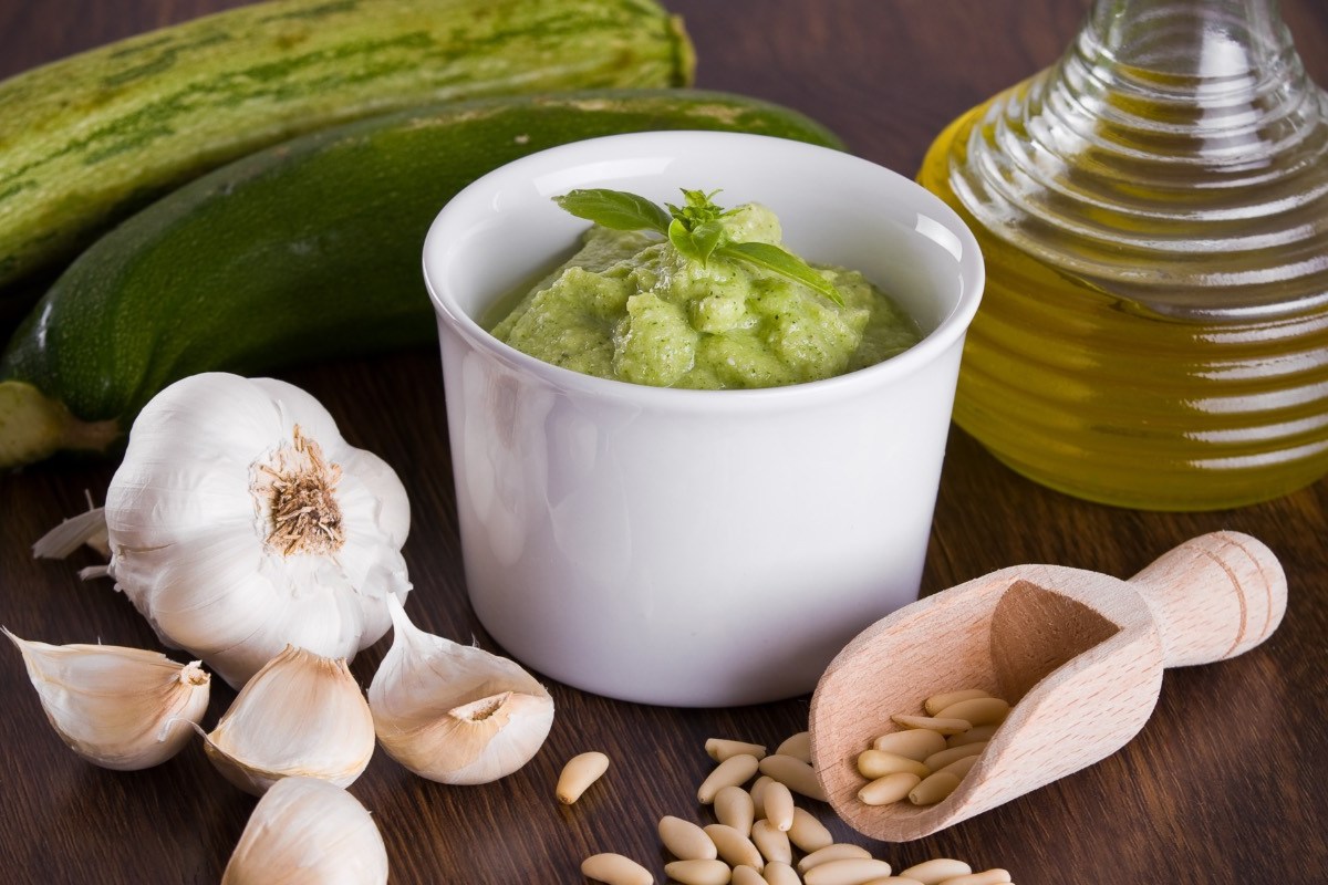 Un plato con pesto de calabacín. Alrededor, ingredientes frescos.