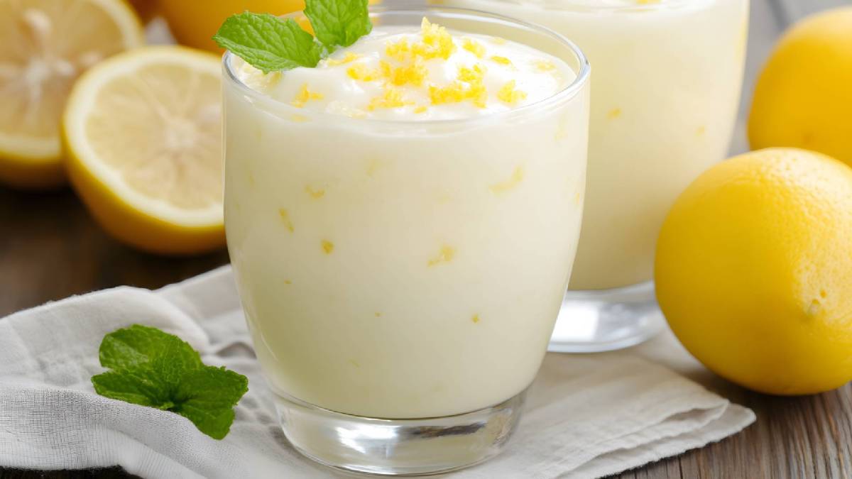 Dos vasos de quark de limón sobre una mesa, con limones al lado